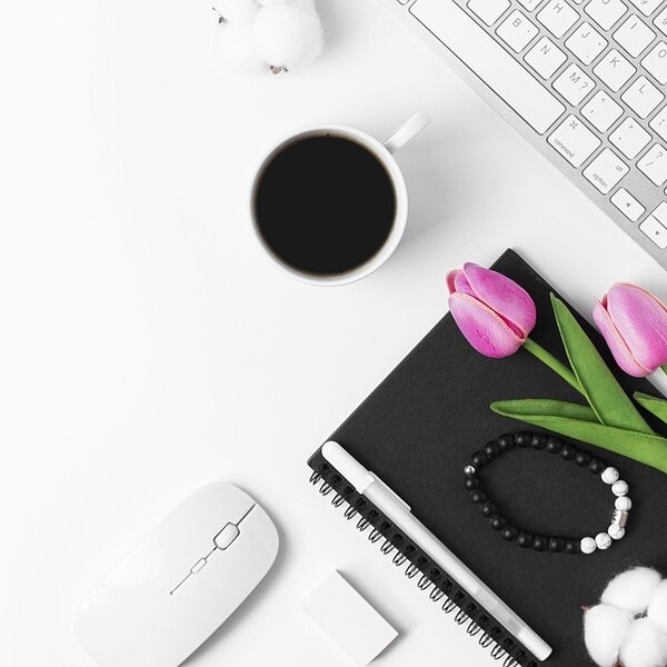Tastatur mit Kaffee, Blumen und Maus